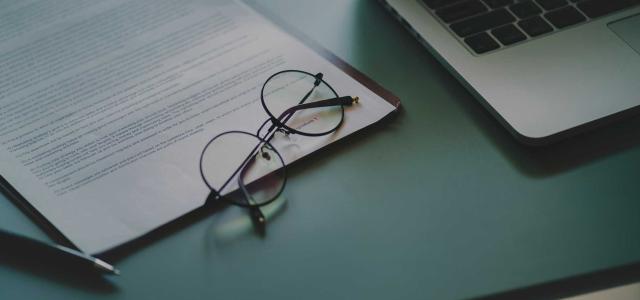 Glasses on a notebook, next to a laptop.